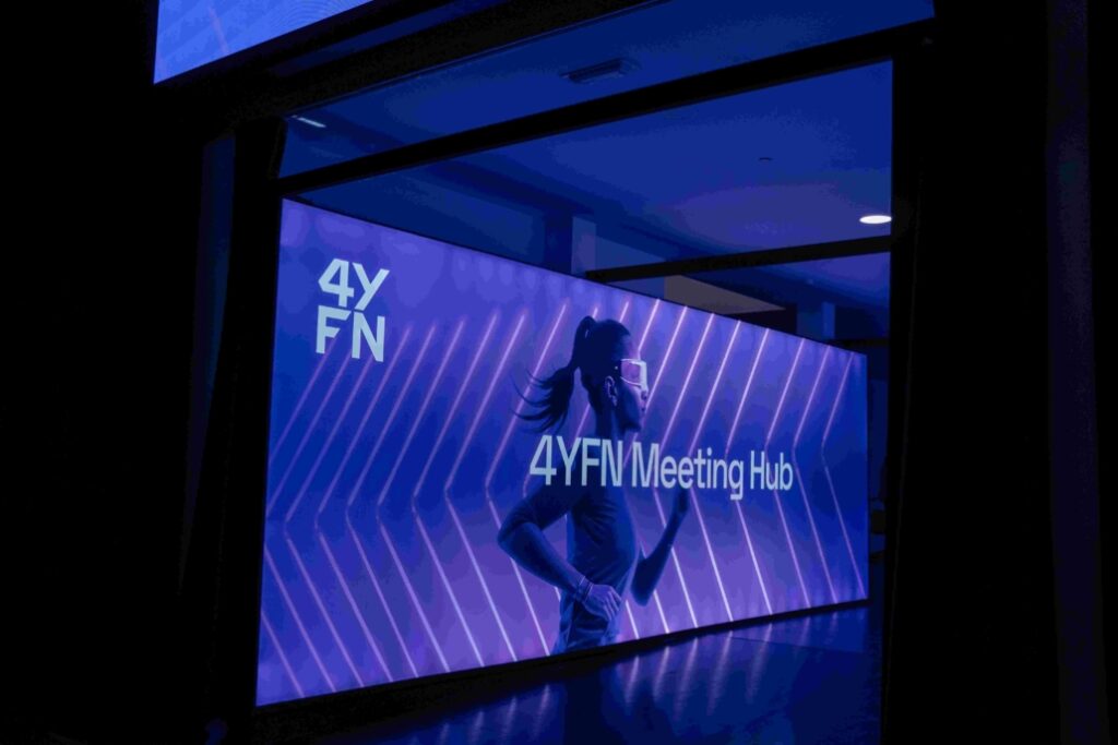 A picture of a screen with the text '4YFN Meeting Hub' and a woman pictured running with glasses on.