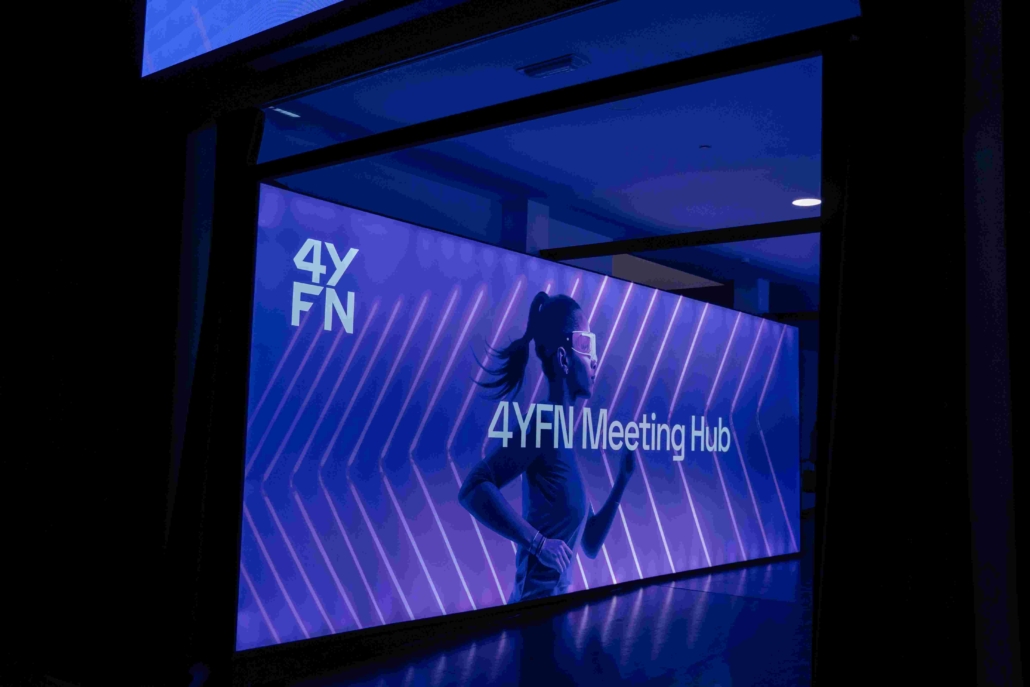 A picture of a screen with the text '4YFN Meeting Hub' and a woman pictured running with glasses on.
