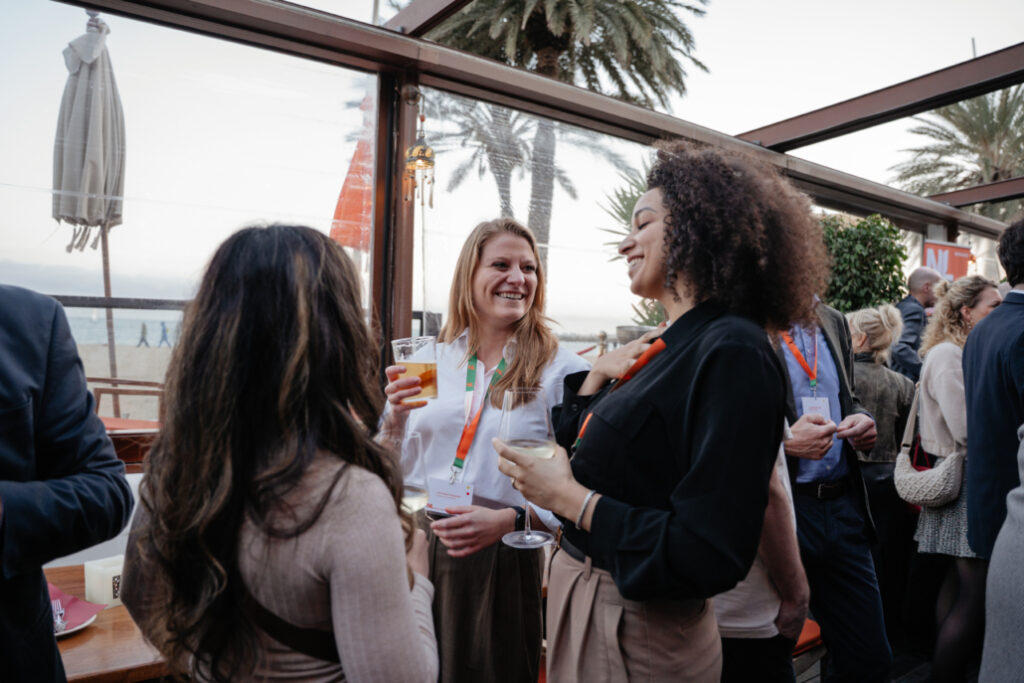 A picture of three women holding drinks and smiling at one another.