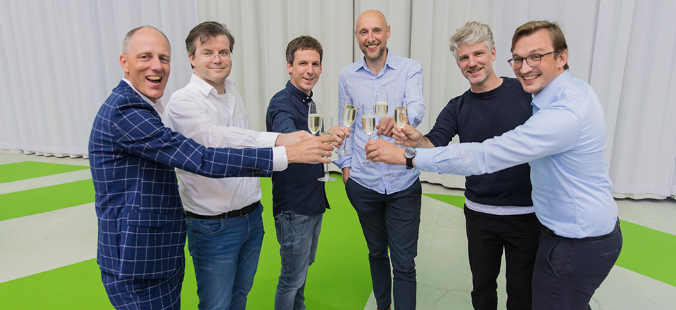 Een foto van het team dat proost met een glas champagne. 