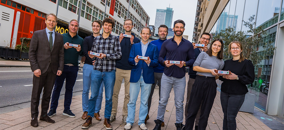 Een persfoto van het UNIIQ team dat de bekende baksteen overhandigd.