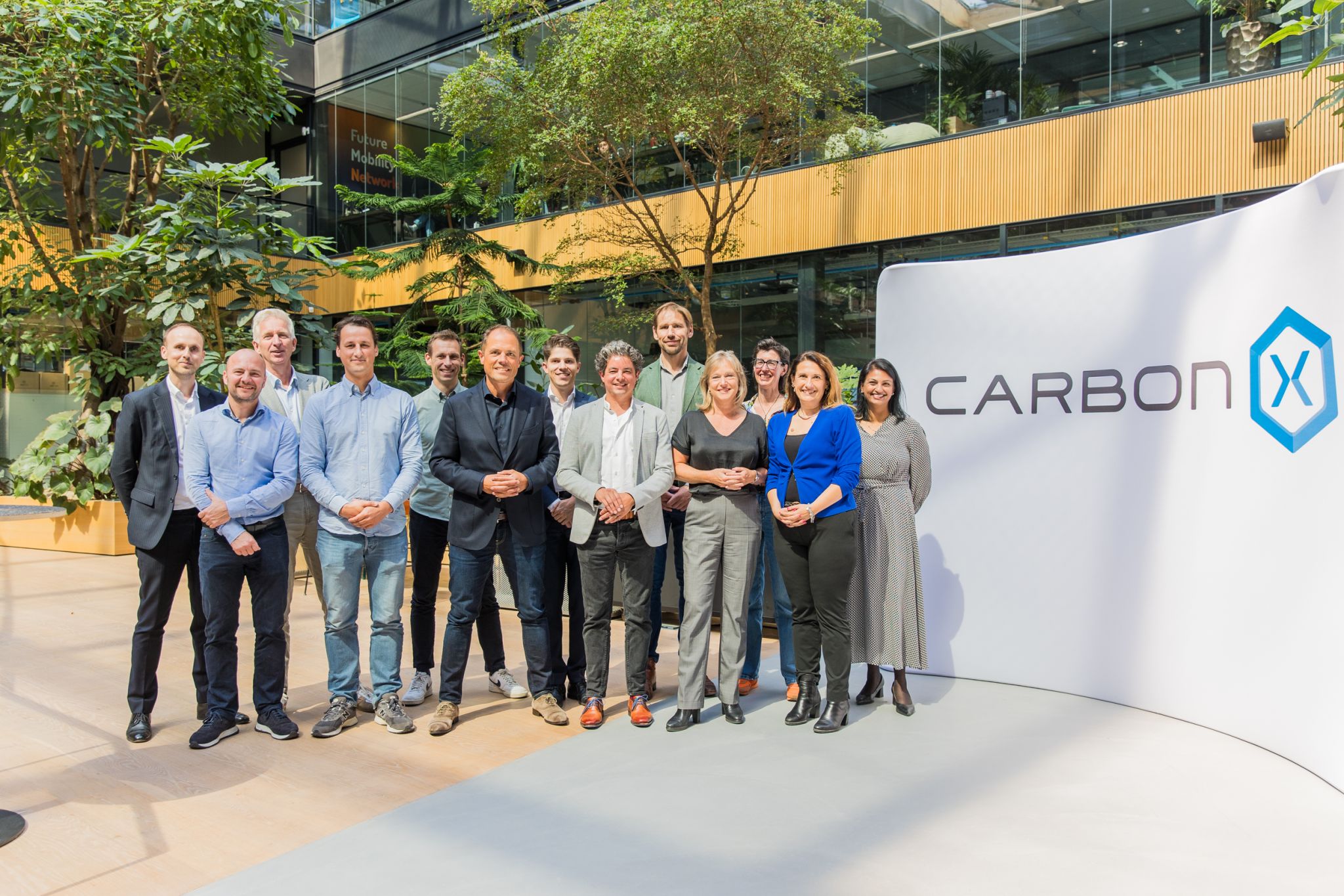 Een CarbonX werkbezoek. Het team gaat naast het logo op de foto.