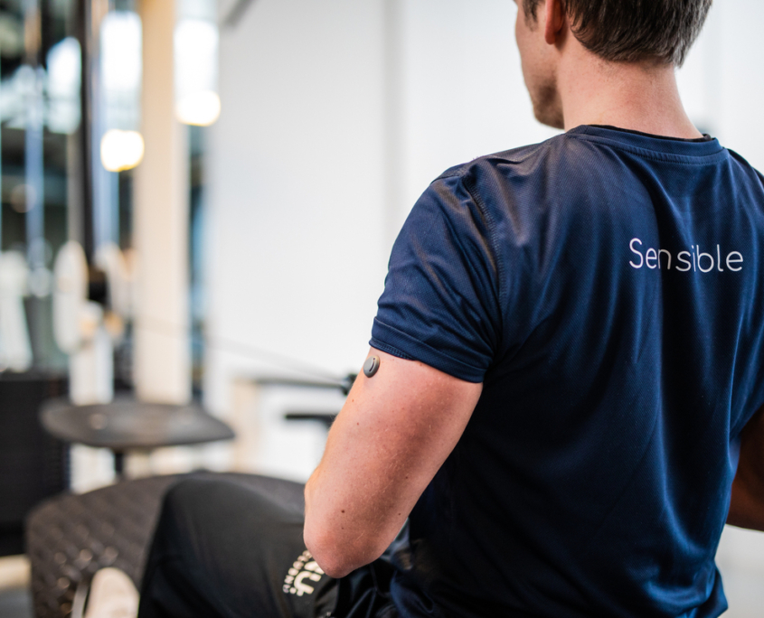 Een foto van een man die in de sportschool aan het sporten is met een 'Sensible' T-shirt aan.